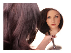 Young Woman Looking at Herself in Mirror